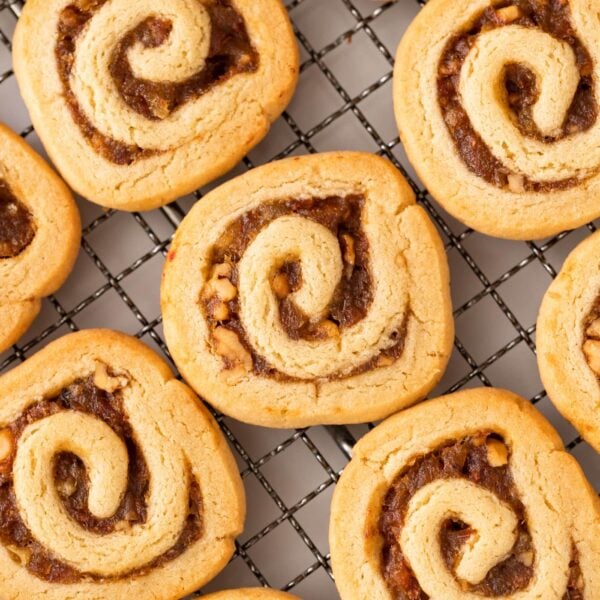 Top down view of pinwheel cookies filled with dates and walnuts sitting on wire cooling rack after coming out of the oven