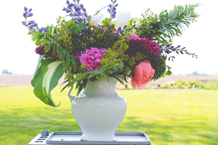 Finished rustic arrangement with lots of different flowers from the garden in an ironstone container during the summer season.