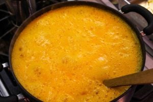 Boiling apricot butter liquid in black kettle on the stove