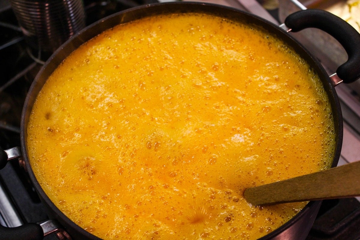 Boiling apricot butter liquid in black kettle on the stove