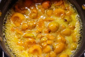 Cooked apricots in liquid in a kettle on the stove
