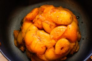 Apricots sitting in a pile in a black-lined kettle on the stove