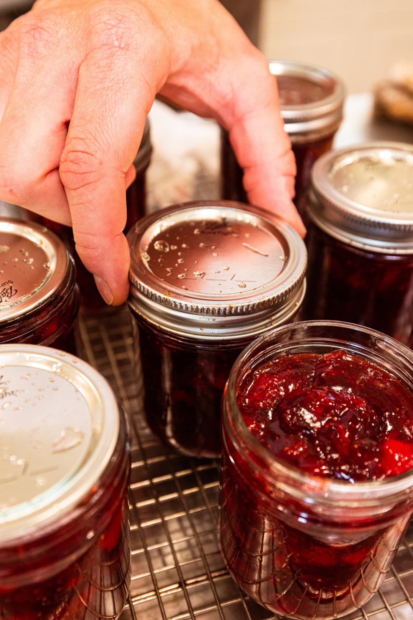 Ring being secured on top of jam jar for canning.