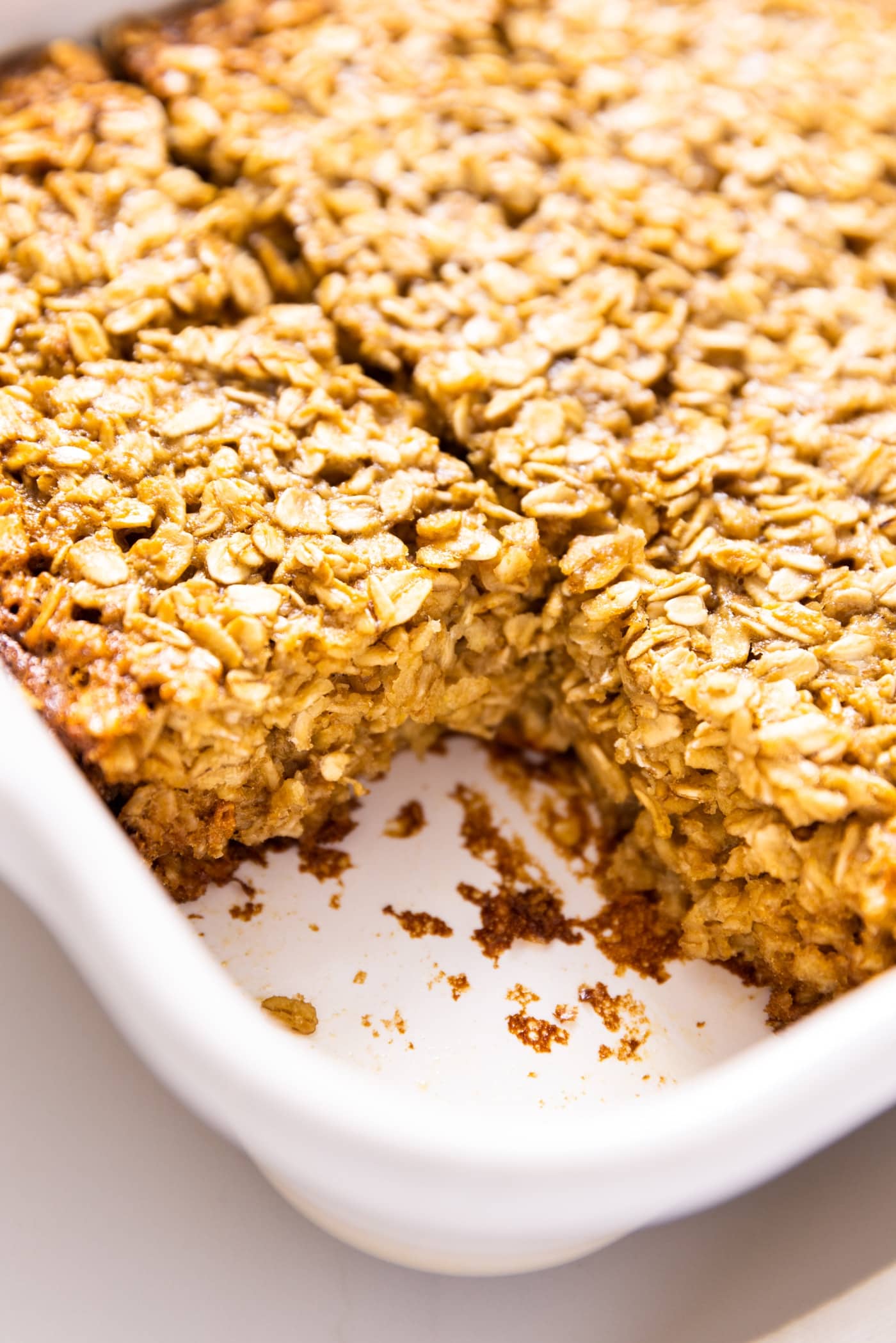 White baking dish with golden brown baked oatmeal inside after coming out of the oven with square slice removed