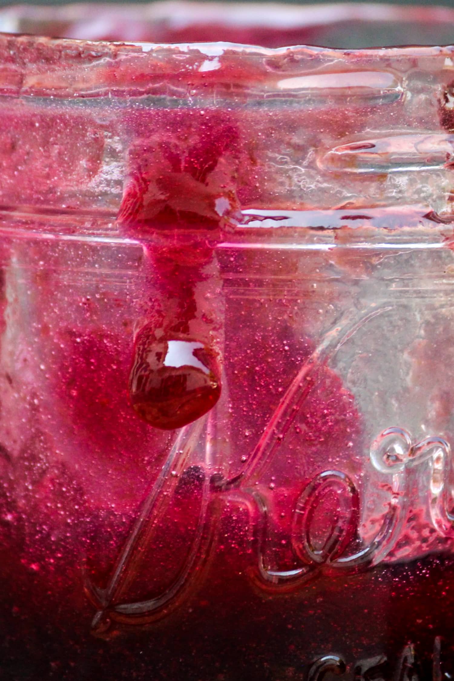 Single bead of grape butter running down the side of jam jar filled with purple grape butter