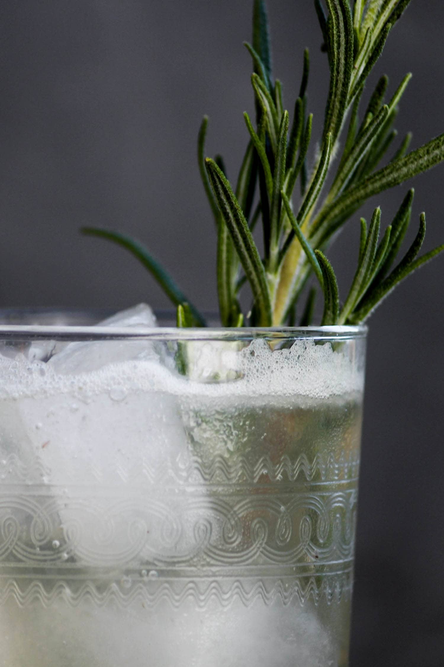 Venetian lemonade in decorative glass with bubbles to the surface with a sprig of rosemary for garnish on a gray slate surface