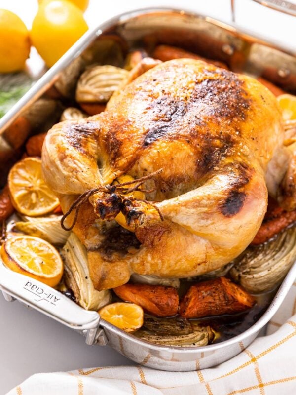 Large roasting pan filled with chicken breast that roasted in the oven with lemons in background