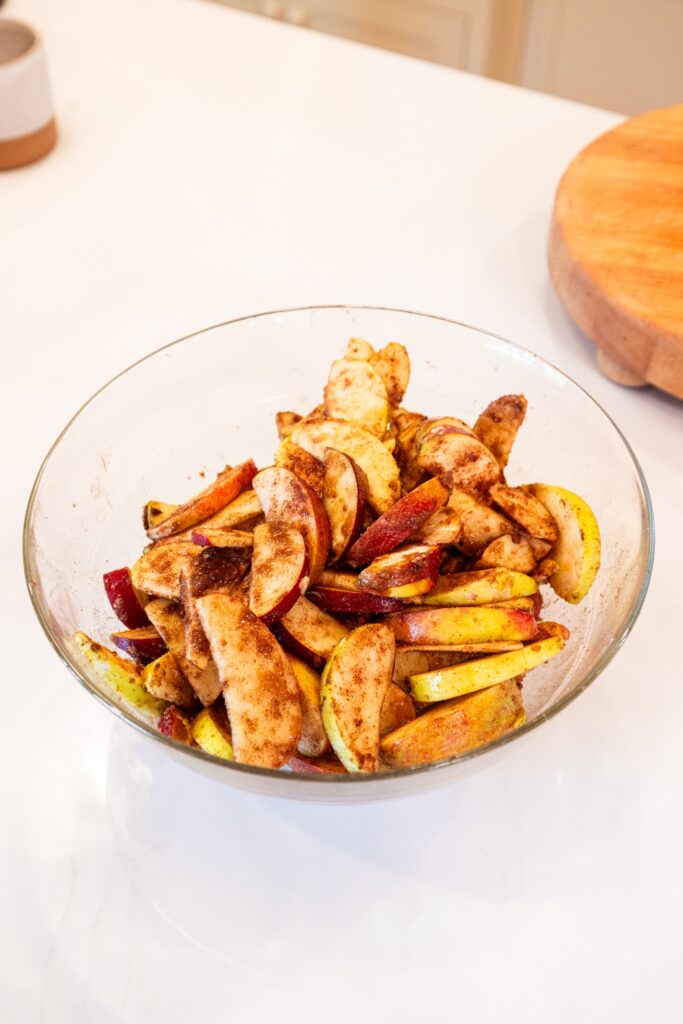 Glass bowl with mixture of sliced apples with cinnamon.
