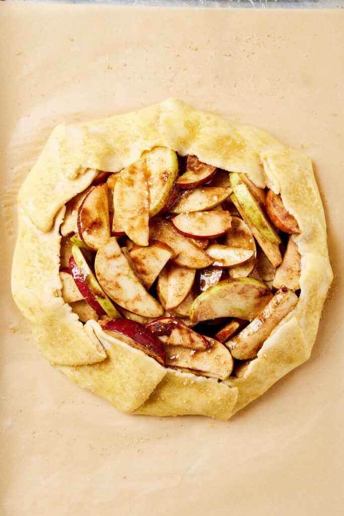 Pie of parchment paper with unbaked apple galette.