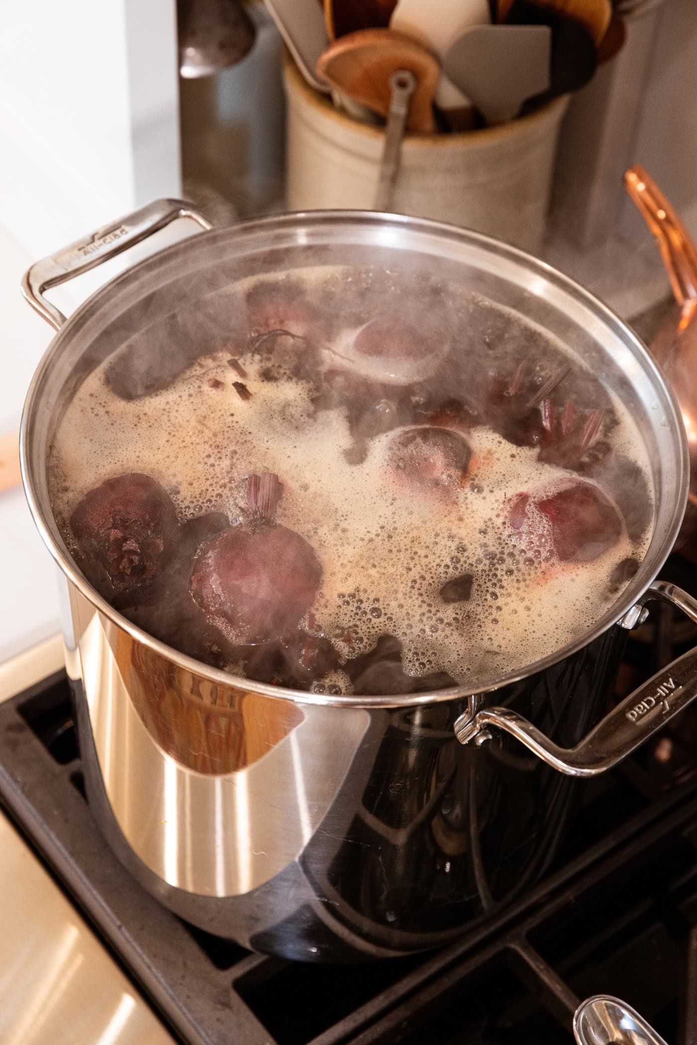 Large stockpot with beet cooking in liquid with foam on the top.