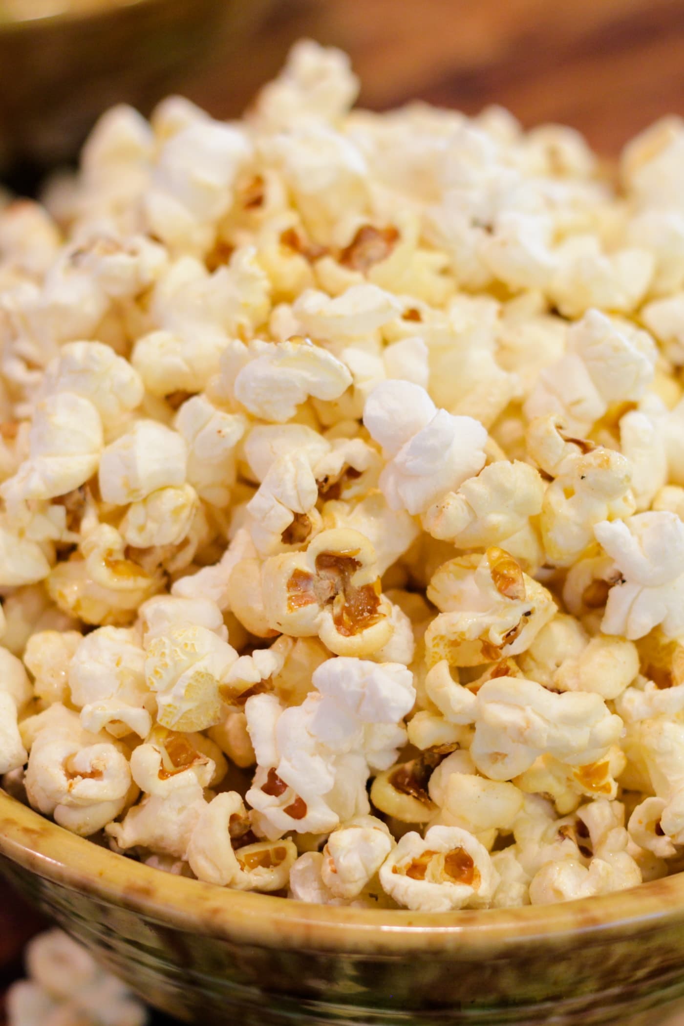 Bowl full of kettle corn sitting on wood surface with extra bowl in background