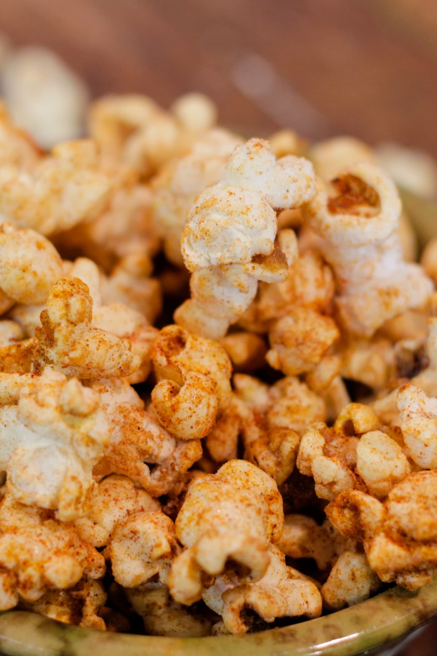 Bowl full of kettle corn sitting on wood surface with extra bowl in background