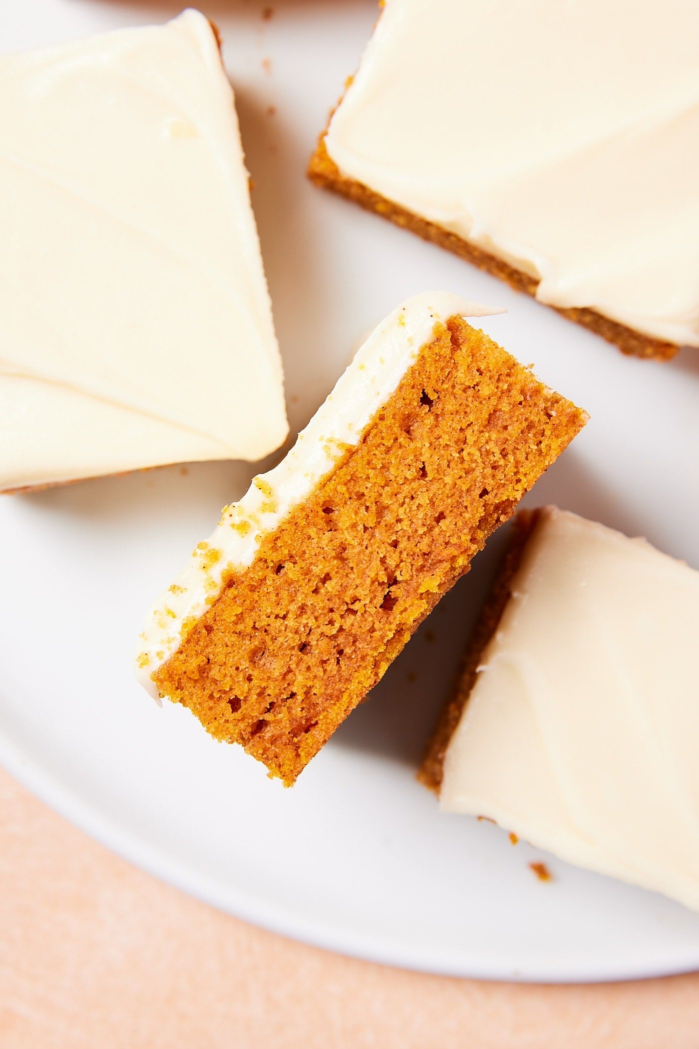Pumpkin bar turned on its side to show interior texture of the bar with cream cheese frosting on top.
