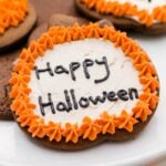 Spiced ginger cutout cookies topped with orange and white frosting sitting on white cake plate