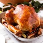 White marble surface with metal roasting pan filled with browned turkey after coming out of oven.