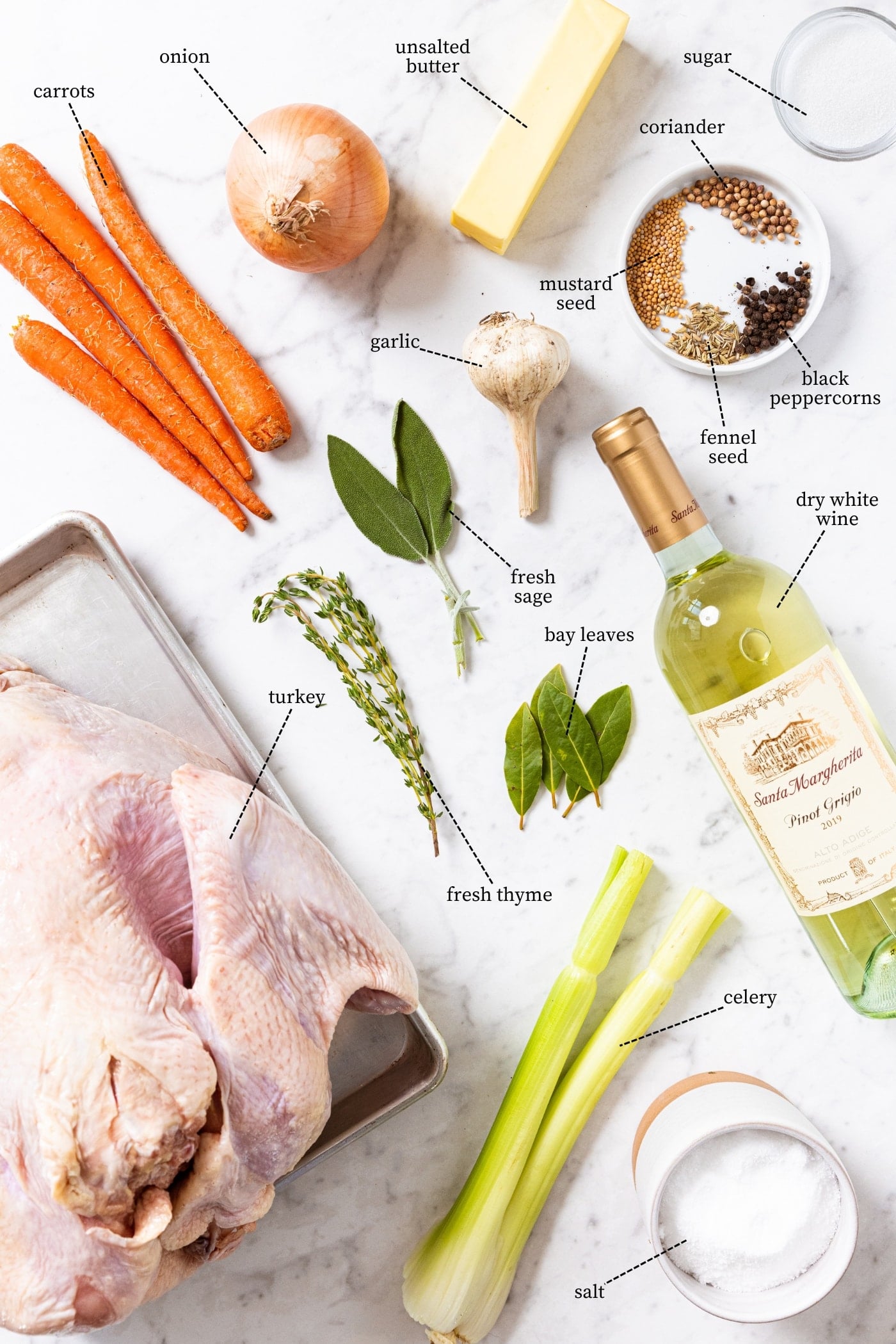 Marble surface filled all ingredients needed to make a classic Thanksgiving turkey including raw turkey, sage, thyme, carrots, celery, onion, wine, spices, and more.