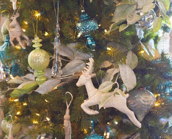 Christmas tree with blue and green ornaments along with a jumping deer.