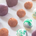 Three different types of decadent truffles sitting on white surface with rows of chocolate lined up