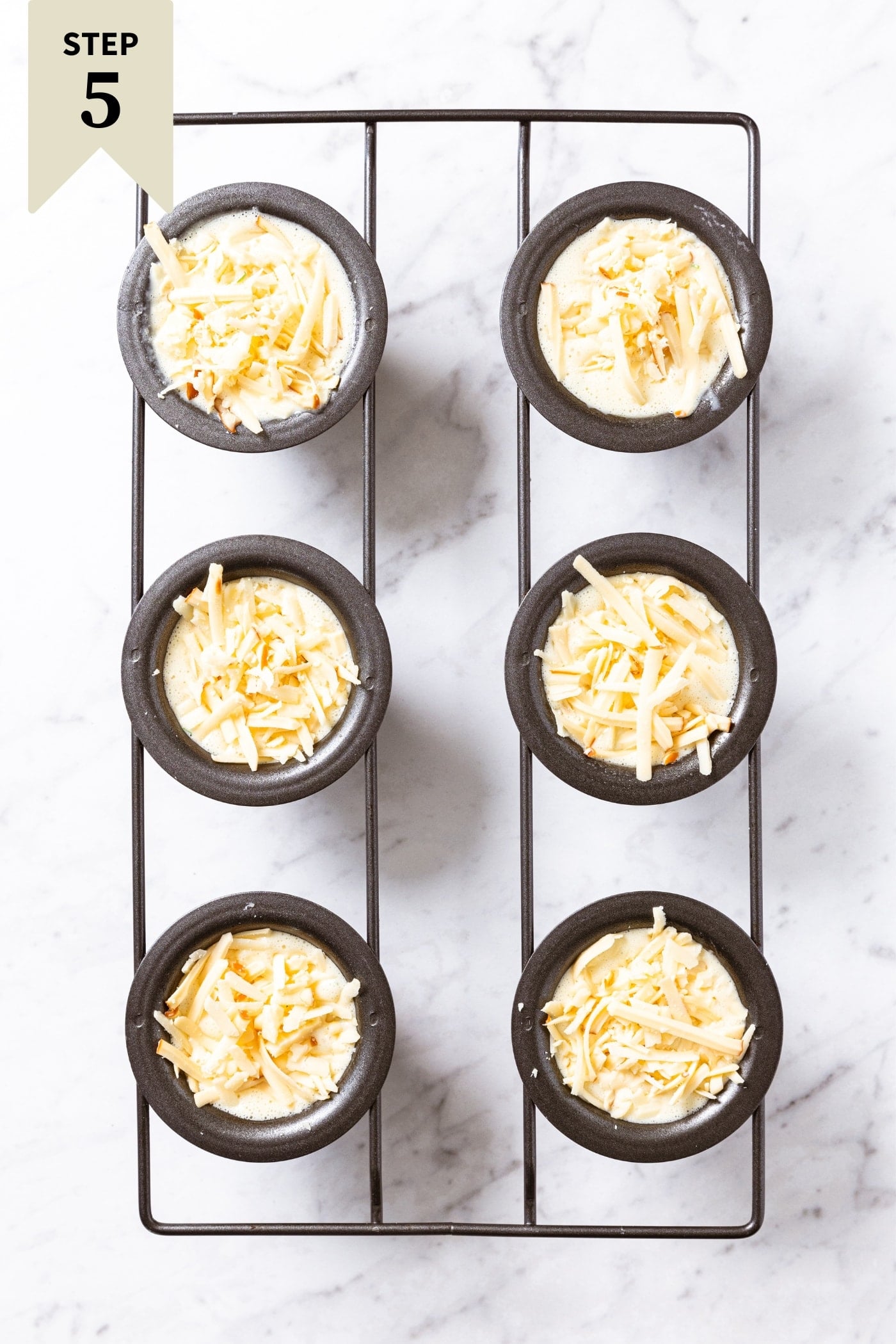 Popover pan with batter in each well before going into the oven to be baked all on marble surface.