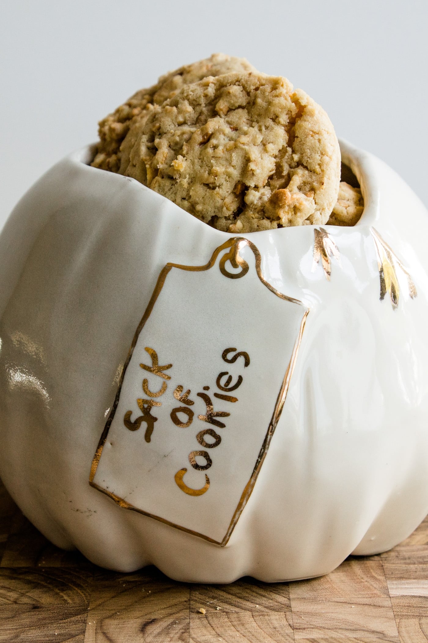 Light brown crunchy peanut cookies sitting in a sack of cookies cookie jar on a wood cutting board
