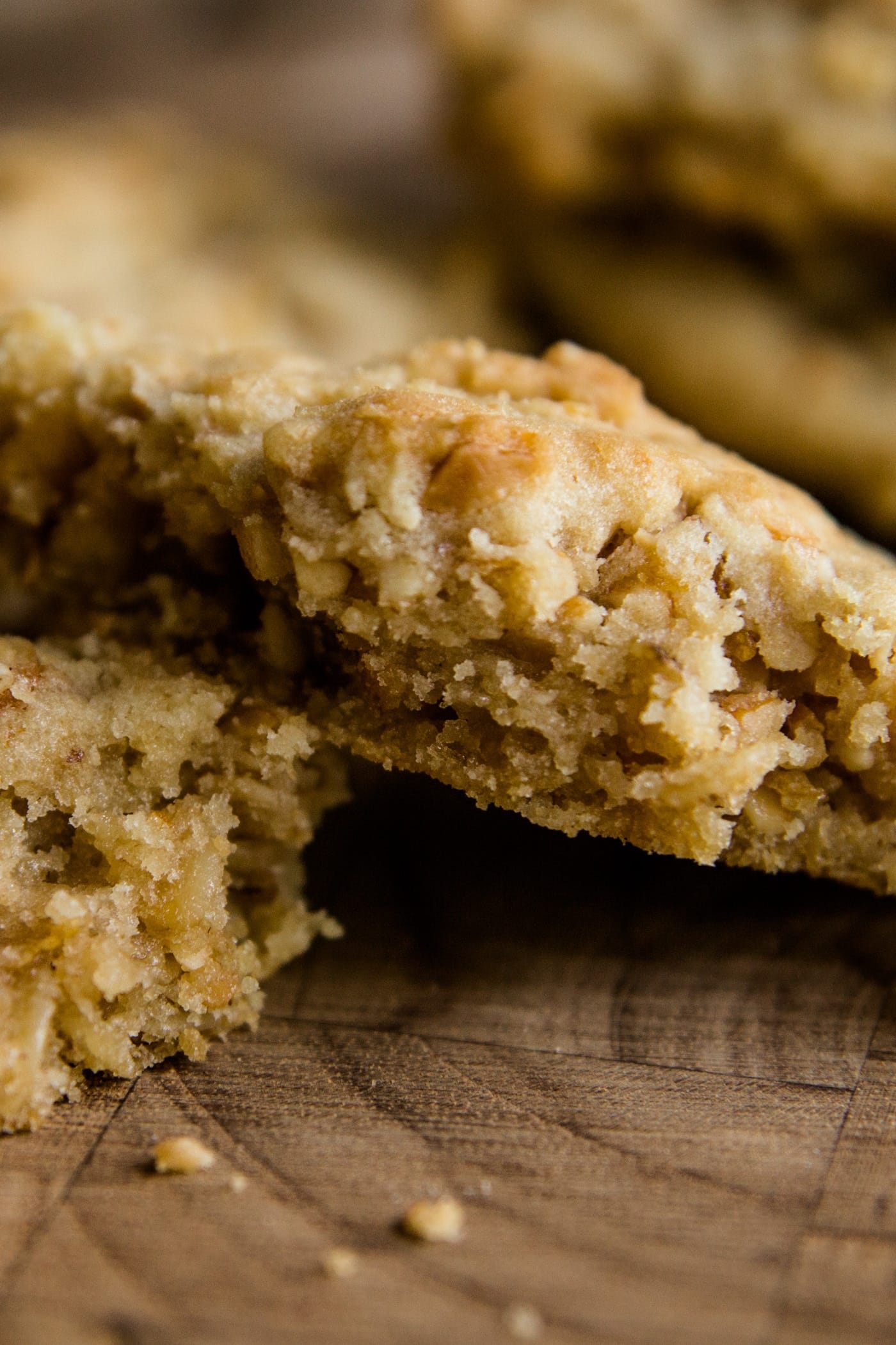 Light brown crunchy peanut cookies broken apart and sitting on a wood cutting board