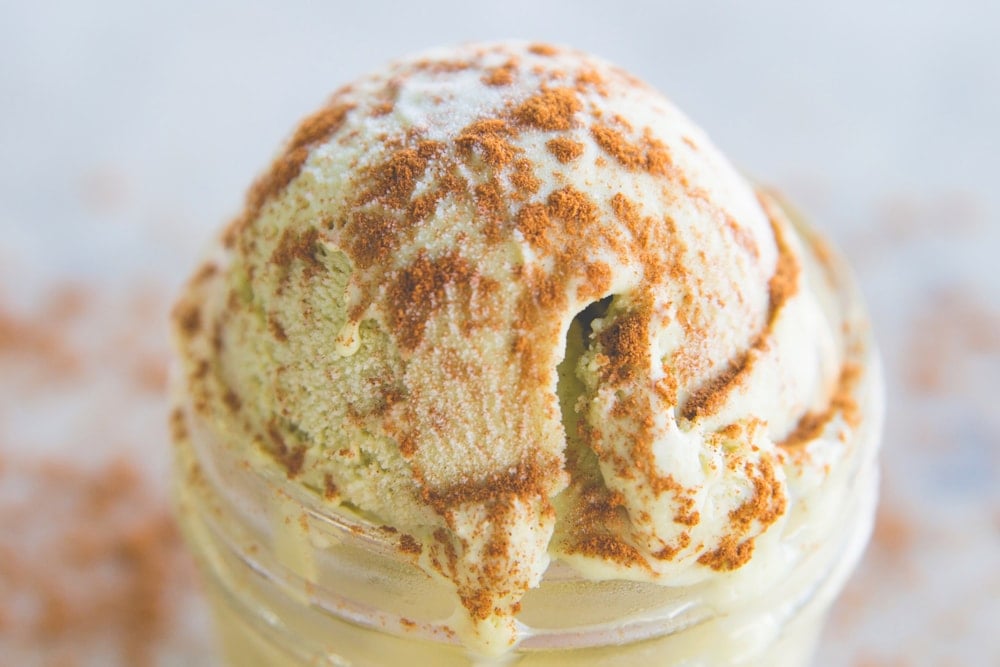 Close up view of green colored matcha ice cream with cinnamon sprinkled over the top and on surface below