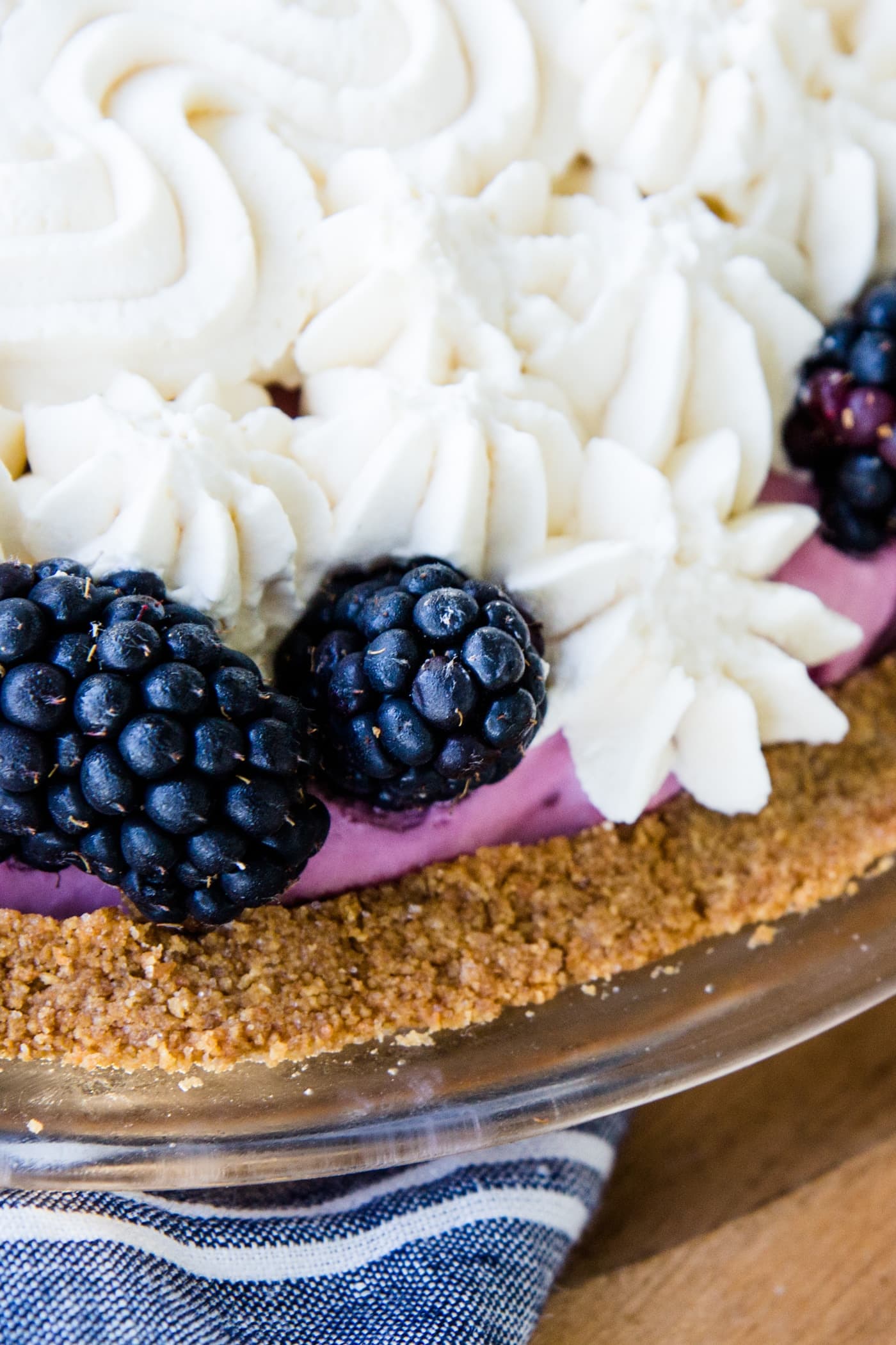 Blackberries sitting on whipped cream in a blackberry icebox pie on wooden surface.