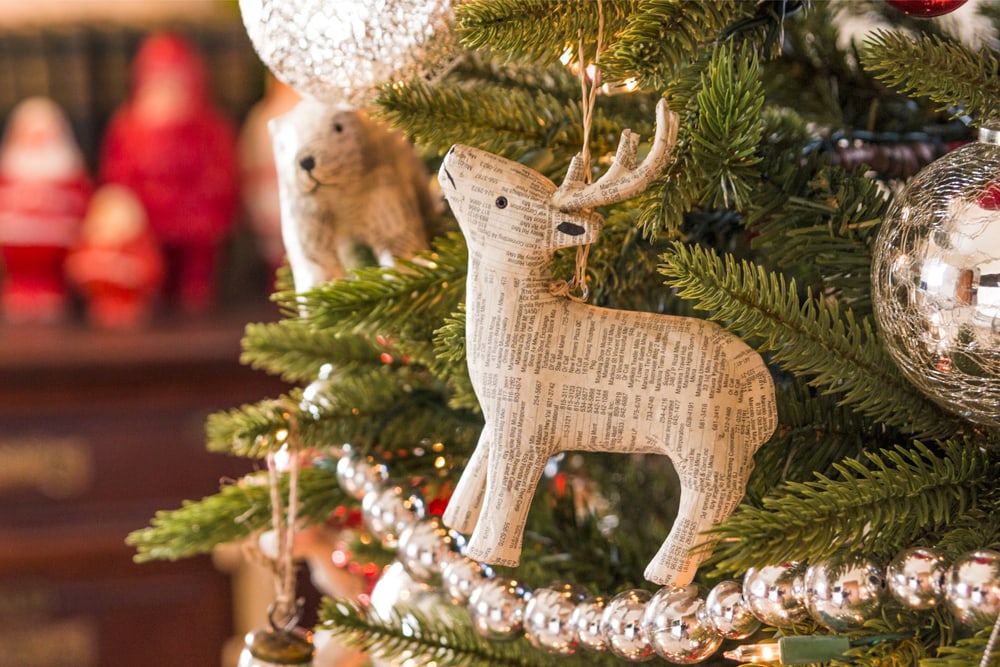 Newspaper ornament on a Christmas tree with garland wrapped around.