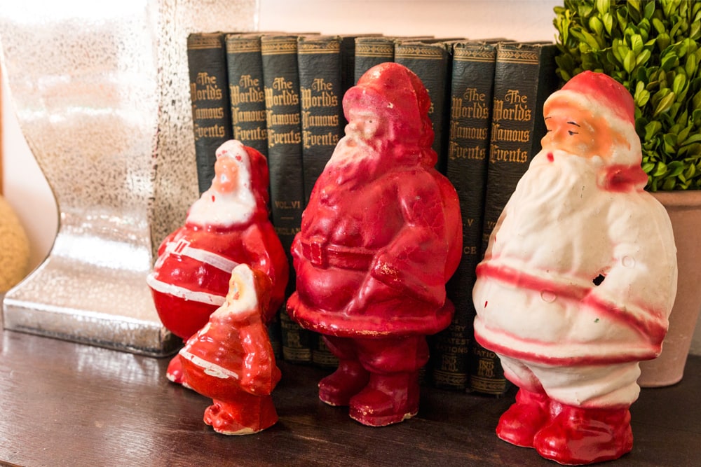 Four red and white santas sitting on an end table for Christmas decor.