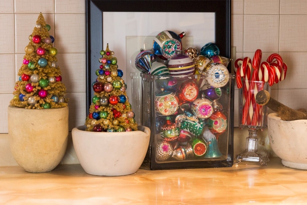 Orange colored countertop filled with bowls with small vintage brightly-colored ornaments and glass candy canes.
