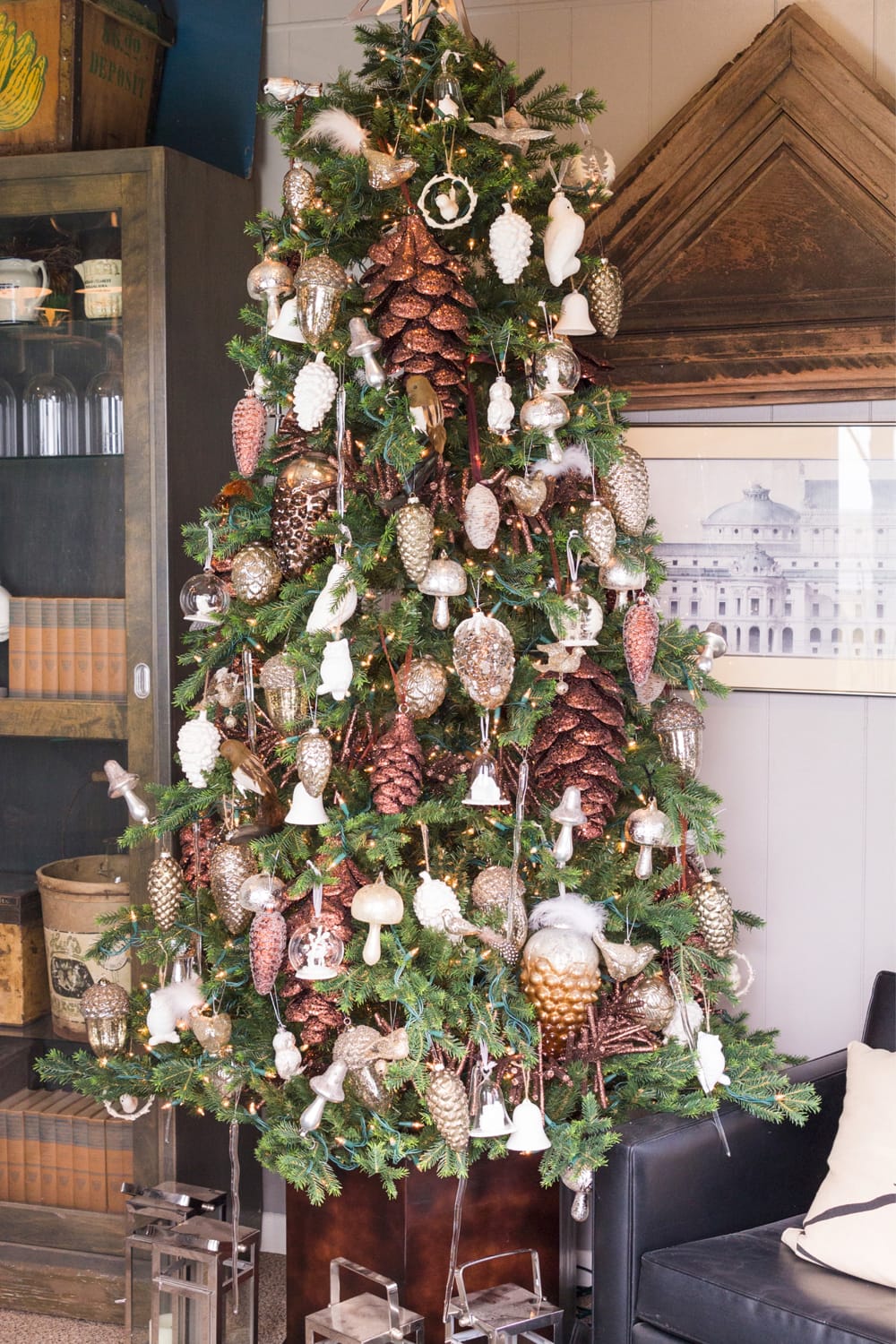 Christmas tree filled with mushroom ornaments with bookcase and pictures in background for holiday home tour.