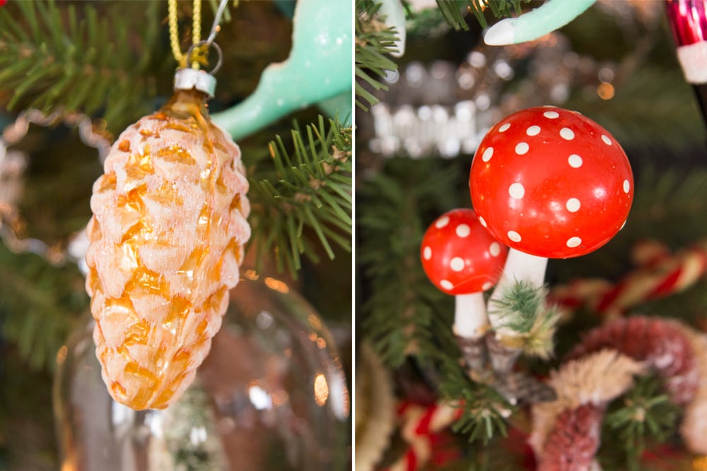 Two ornaments with one a mushroom and one a pinecone on a tree.