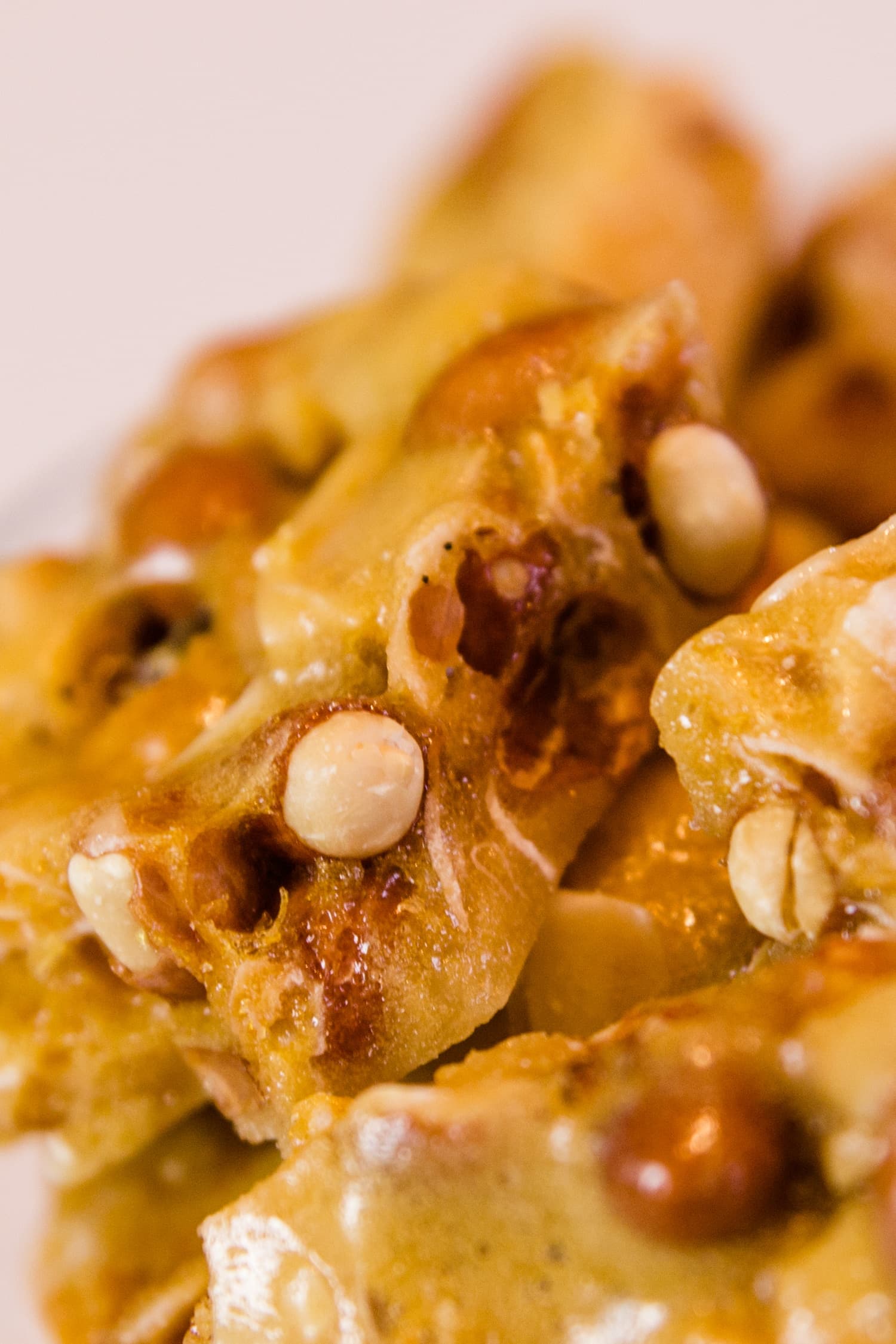 Golden peco candy with peanuts and flakes of coconut piled high on a white surface