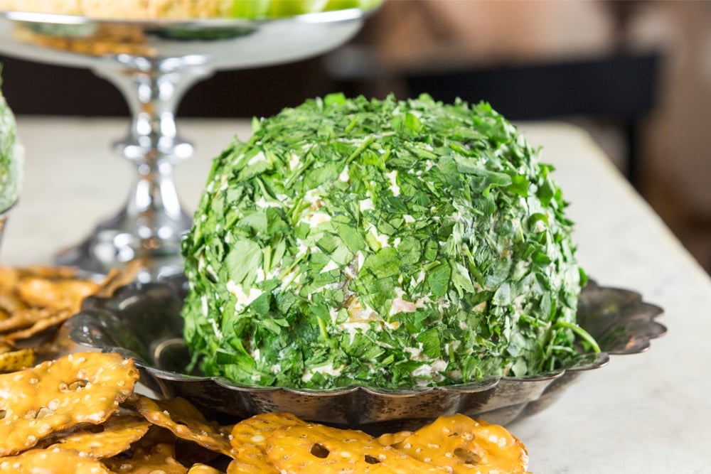 Smoked salmon cheese ball covered in parsley sitting in silver metal bowl with pretzels