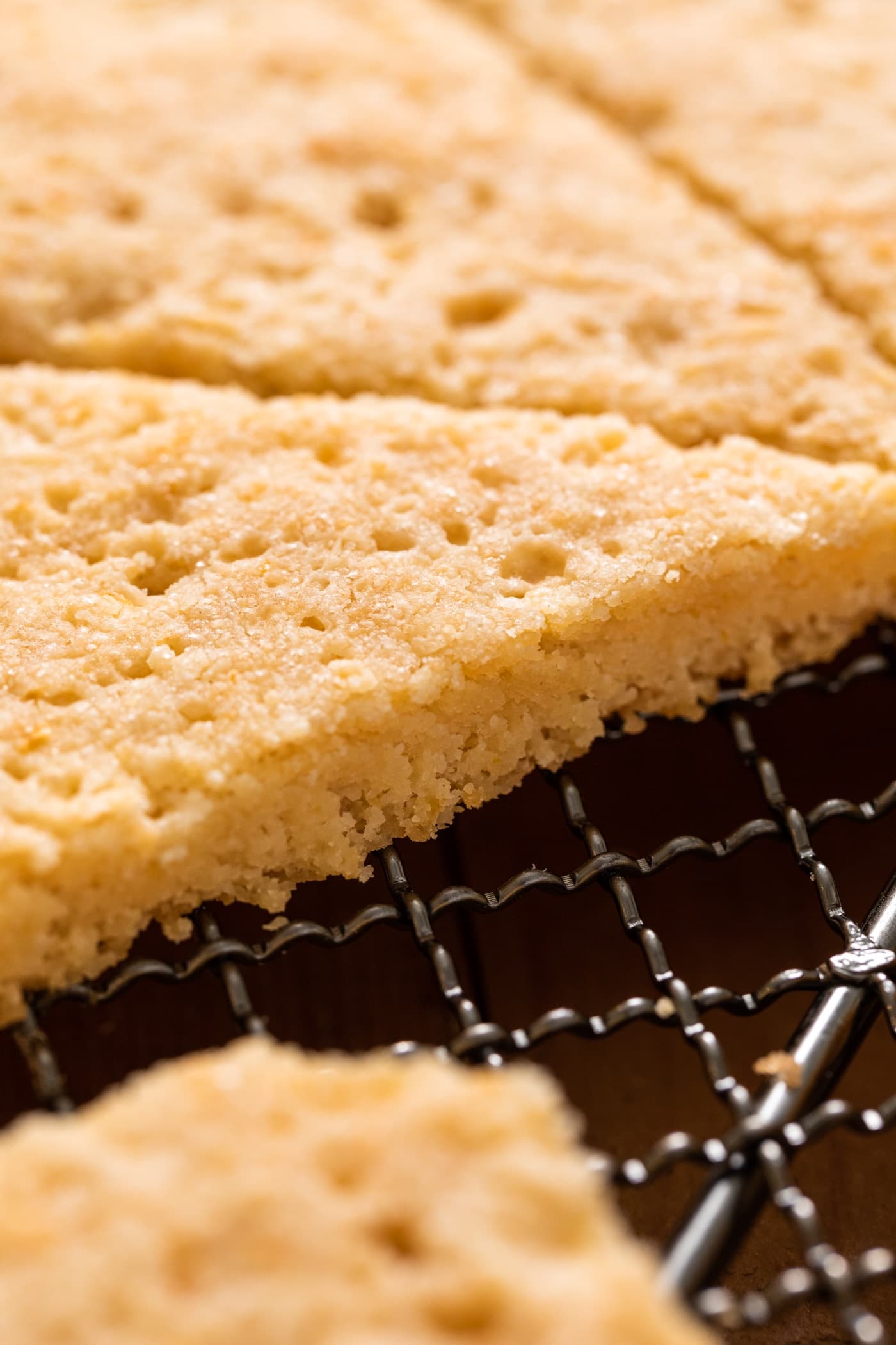 Close up view of golden colored lemon shortbread cookies sitting on metal cooling rack