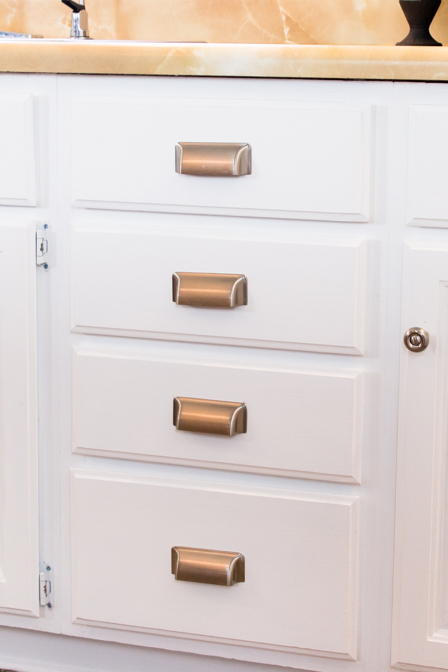 Matte silver drawer pulls attached to bright white lower kitchen cabinets