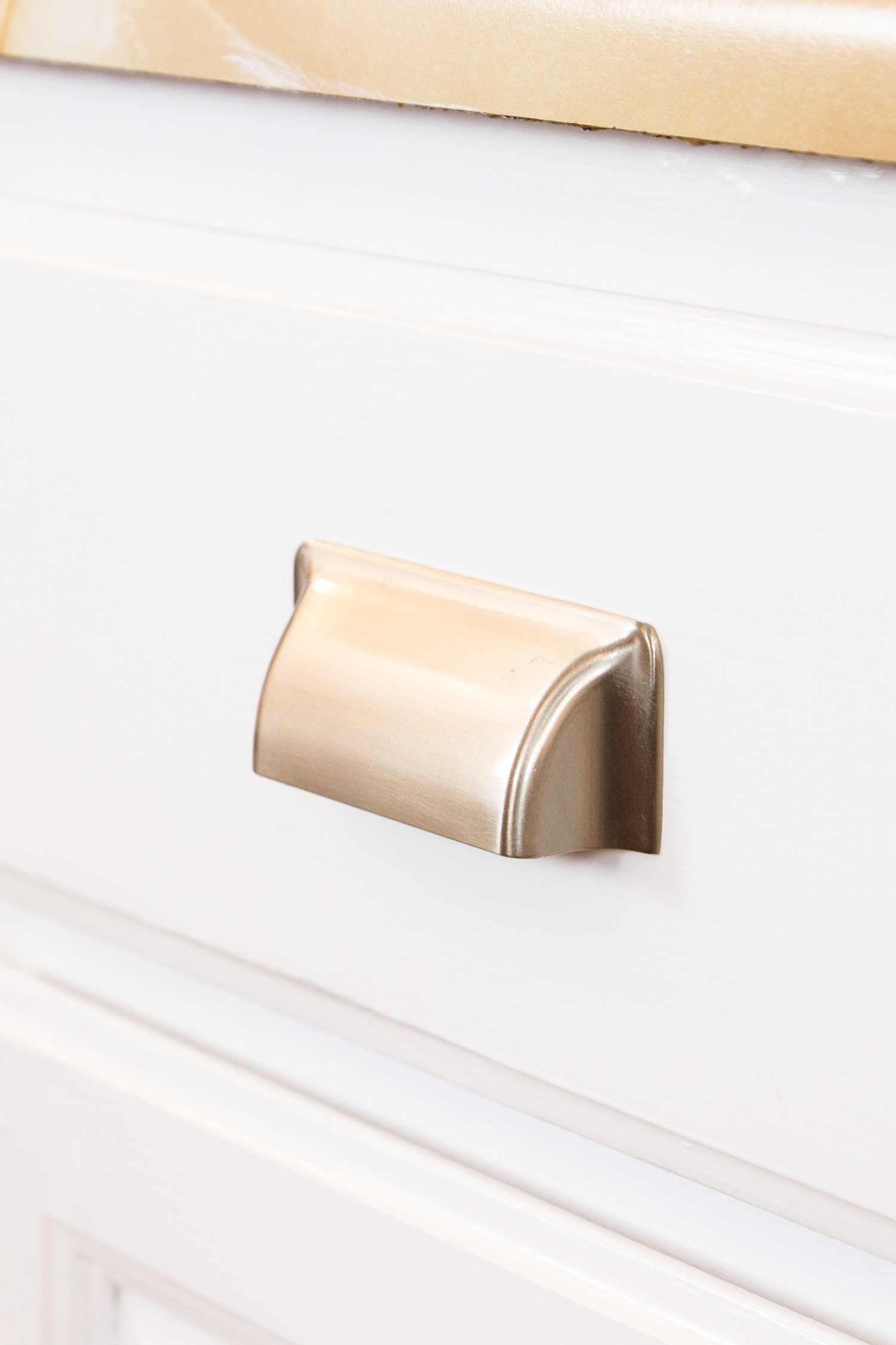 Matte silver drawer pulls attached to bright white lower kitchen cabinets