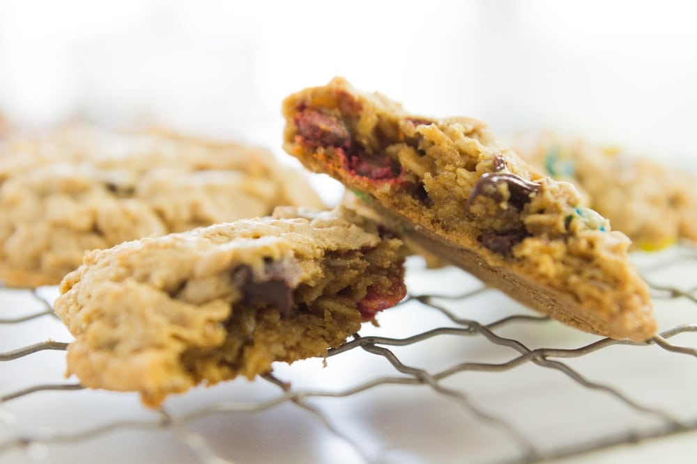 One monster cookie broken in half sitting on cooling rack showing inside of cookie with white surface underneath