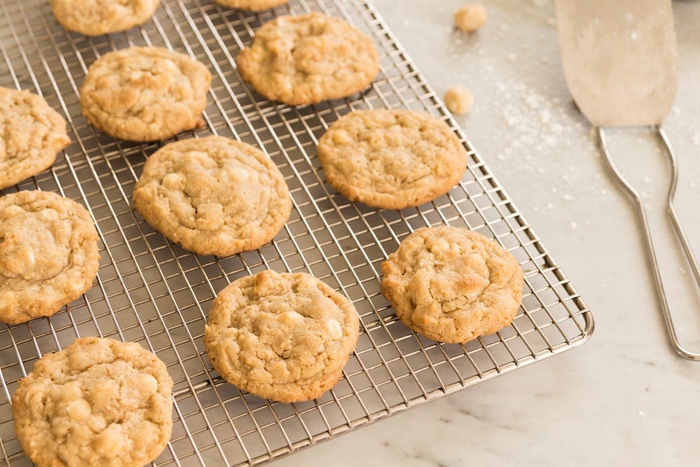 Wire cooling rack with light brown cookies sitting on top with scoop off to the side