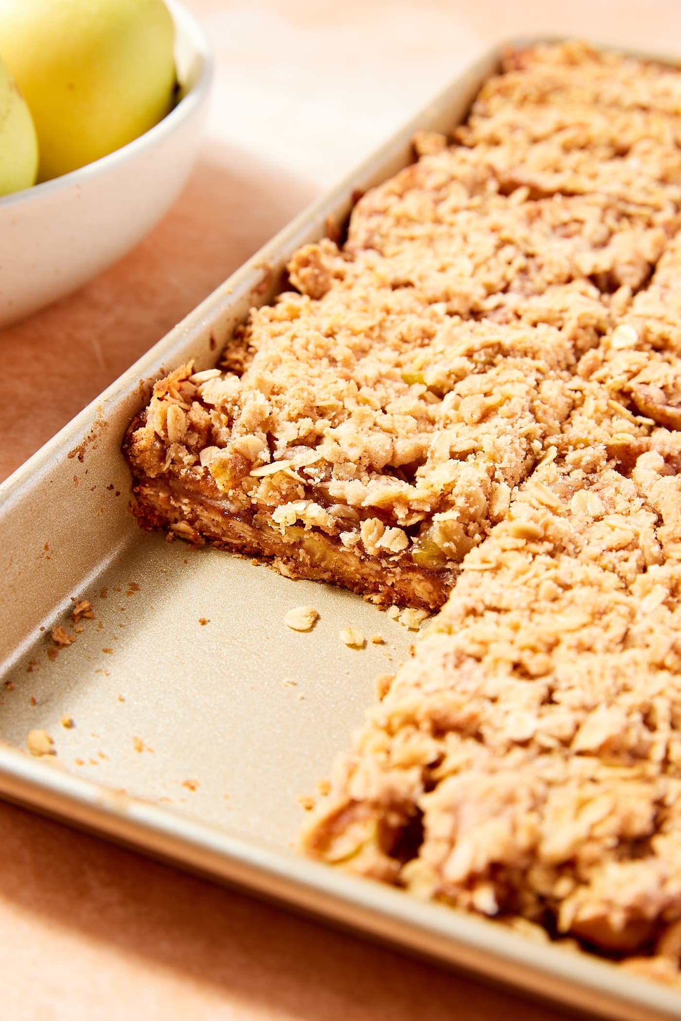 Gold baking pan filled with apple pie bars with slices cut showing interior texture of the bars.