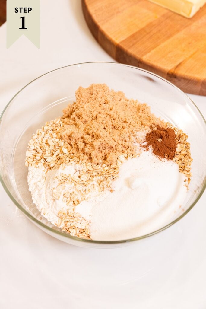 Glass measuring cup filled with separate components of sugar, flour, brown sugar, and spices all on white surface.