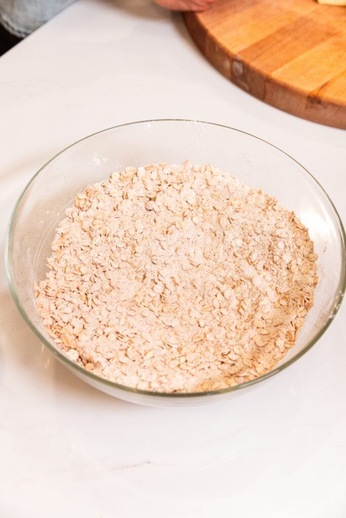 Combined mixture of sugars with flour in a large glass measuring bowl on a white surface.