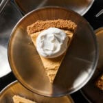 Silver plate with slice of frozen pumpkin cheesecake with dollop of whipped cream.