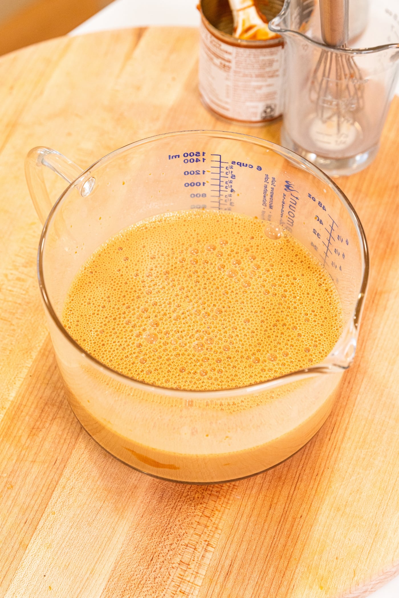 Large glass measuring cup filled with brown colored dulce de leche mixture.