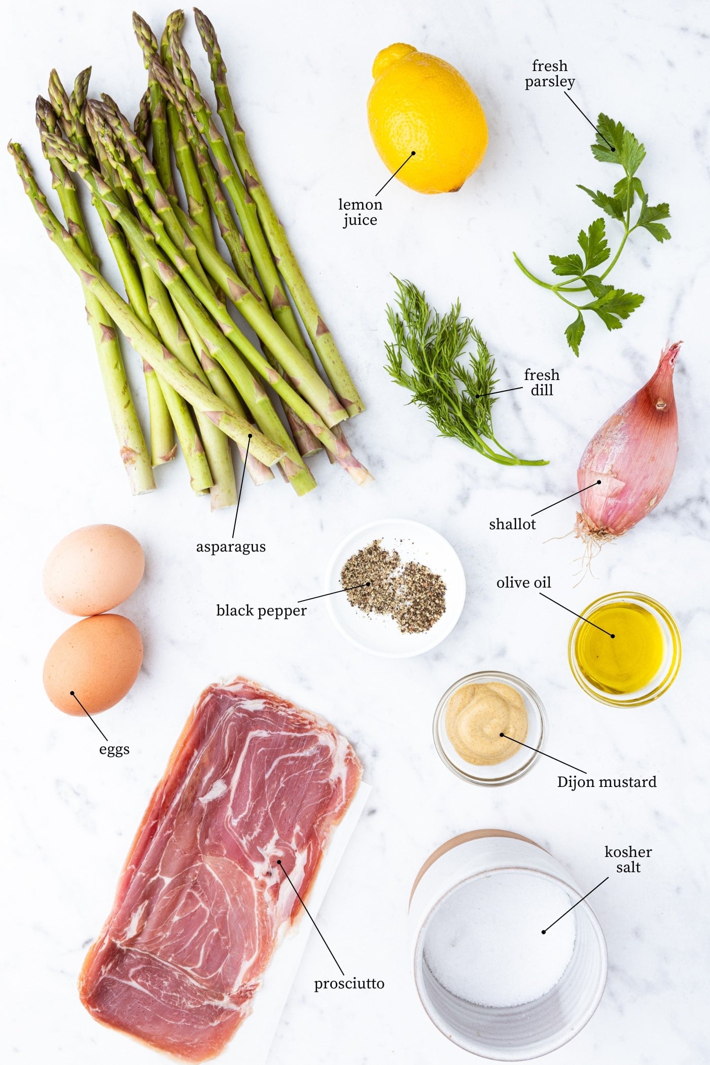 White marble surface filled with all ingredients needed to make roasted asparagus with lemon vinaigrette including asparagus, herbs, spices, eggs, and more.