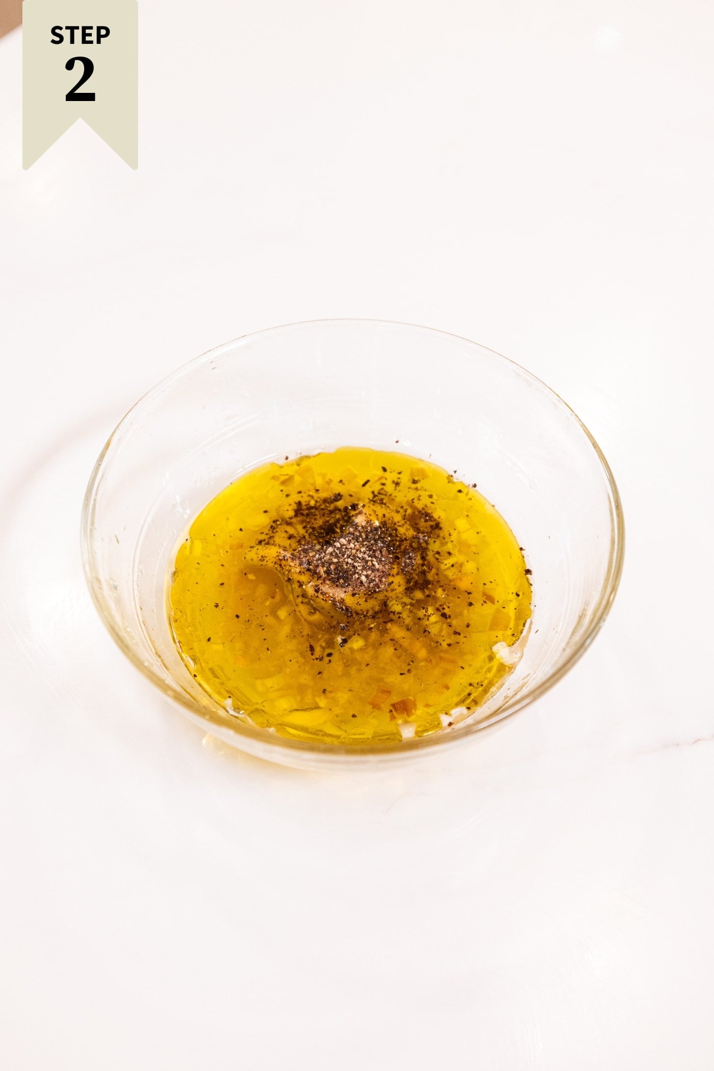 Small glass bowl filled with all ingredients needed to make a quick vinaigrette including oil and mustard.