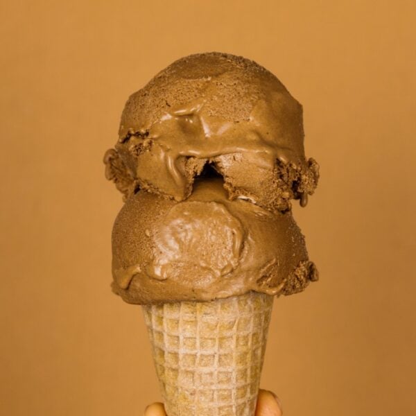 Two scoops of French silk pie ice cream on an ice cream cone with a brown background