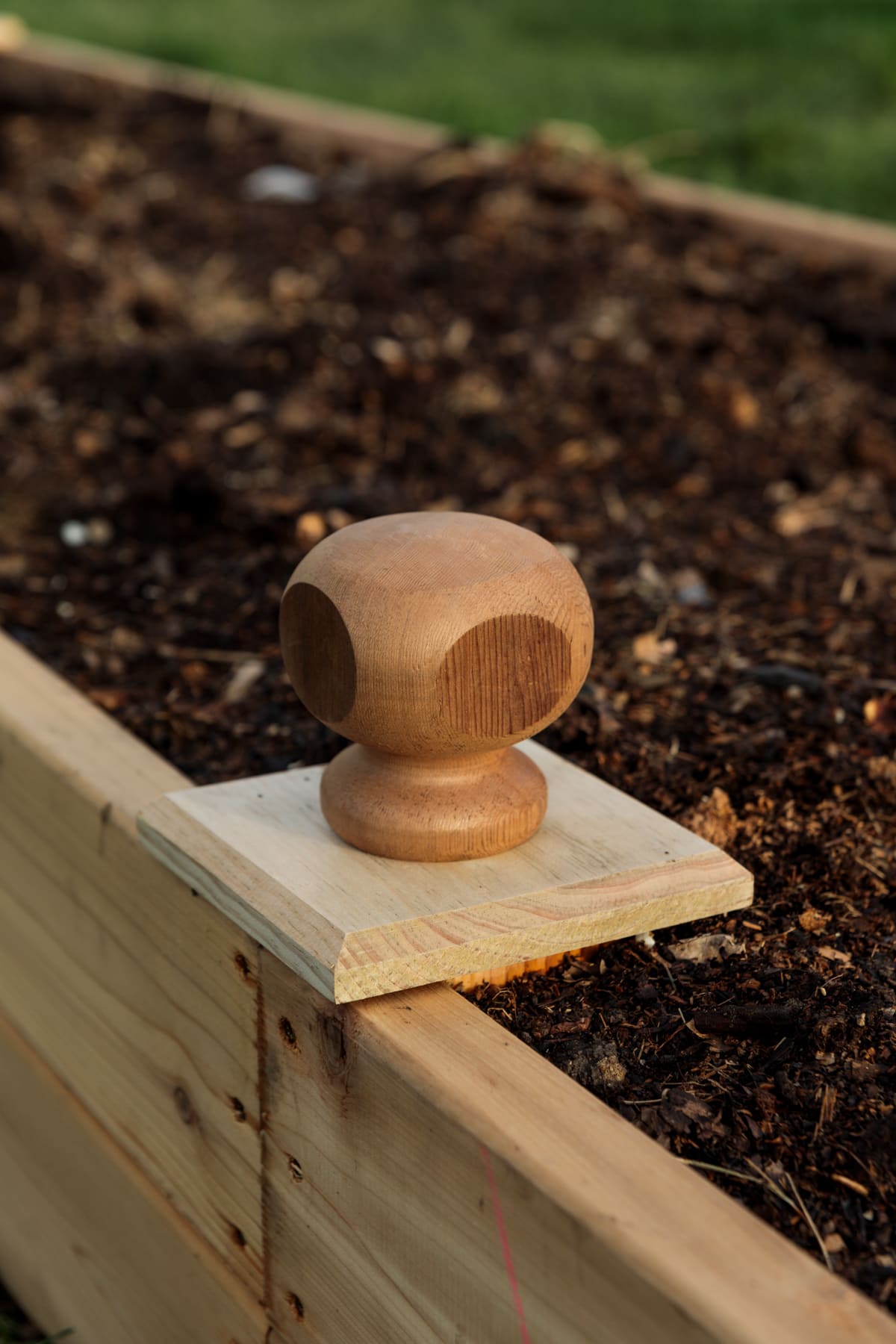 Wood end caps attached to raised garden bed filled with dark rich soil