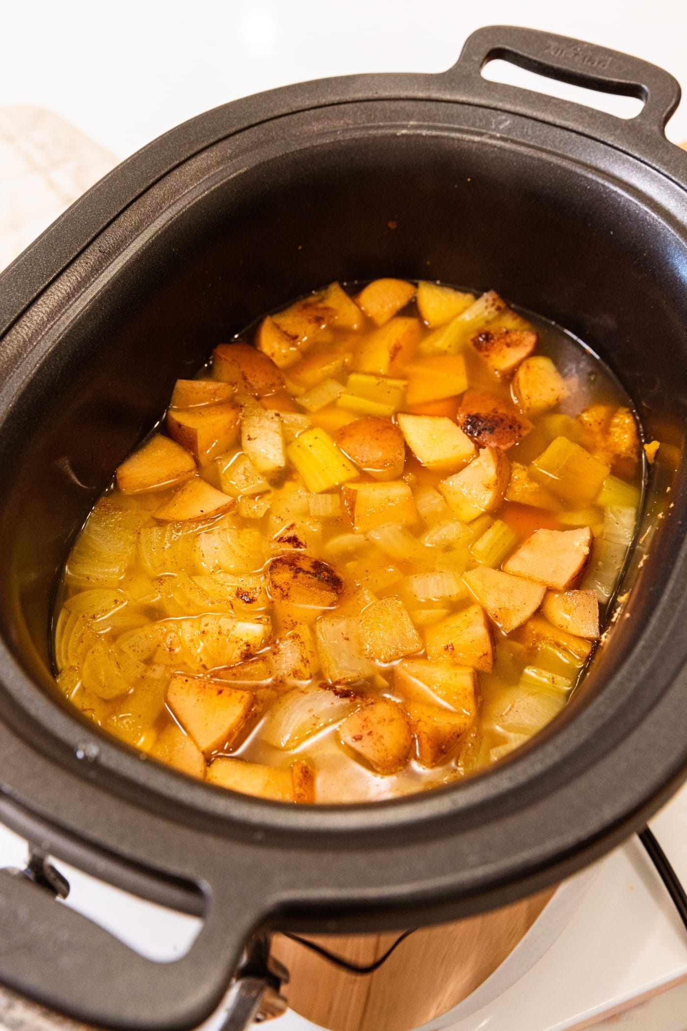 Slow cooker filled with cooked squash and apples to make a squash soup before being blended.