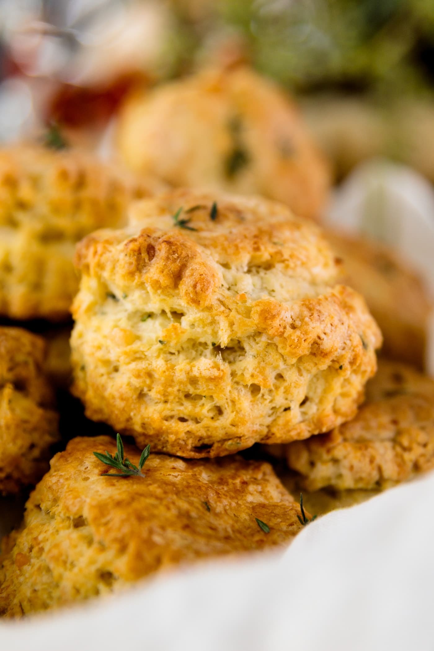 Herb cheese biscuits sitting on white linen with greenery in background
